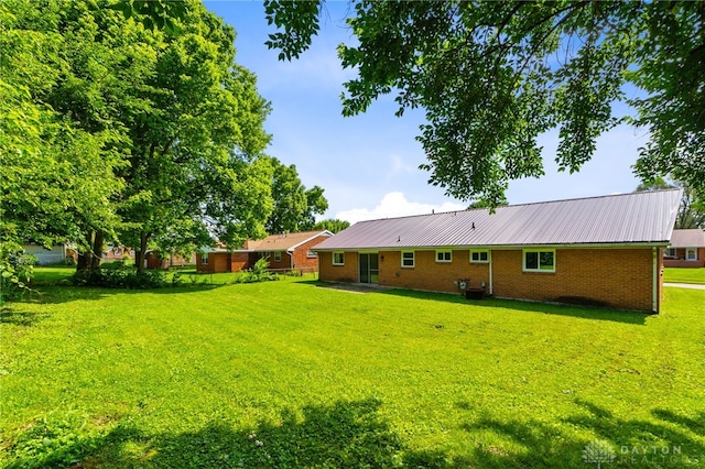 925 Robinette Ave, Vandalia, OH 45377 - rear view of property with brick siding, a yard, and a metal roof