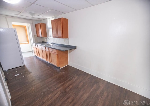 2107 Woodlawn Ave, Middletown, OH 45044 - kitchen featuring freestanding refrigerator, dark wood finished floors, dark countertops, a drop ceiling, and brown cabinetry