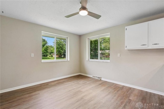 40 Rosewood Dr, Springboro, OH 45066 - empty room with light wood-style floors, healthy amount of natural light, a ceiling fan, and a textured ceiling