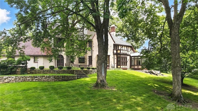 1160 Lytle Ln, Kettering, OH 45409 - view of front facade featuring stucco siding, a front yard, a sunroom, and a chimney