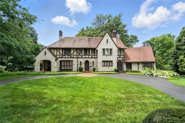 1160 Lytle Ln, Kettering, OH 45409 - tudor home featuring a chimney, curved driveway, stucco siding, and a front yard