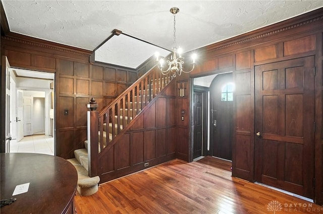 1160 Lytle Ln, Kettering, OH 45409 - foyer featuring a chandelier, stairway, light wood-style floors, ornamental molding, and wood walls