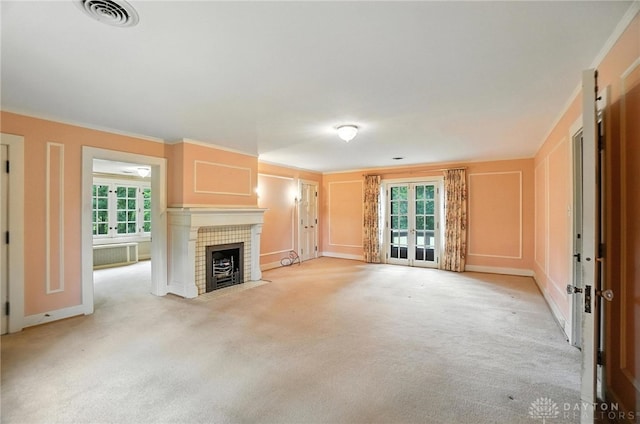 1160 Lytle Ln, Kettering, OH 45409 - unfurnished living room featuring french doors, light carpet, a decorative wall, a tiled fireplace, and crown molding