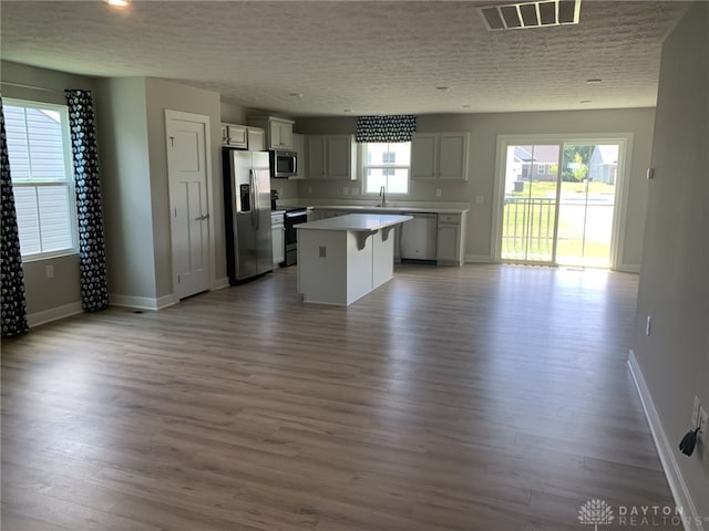 6655 Roycroft Dr, Middletown, OH 45042 - kitchen featuring stainless steel appliances, open floor plan, a center island, wood finished floors, and light countertops