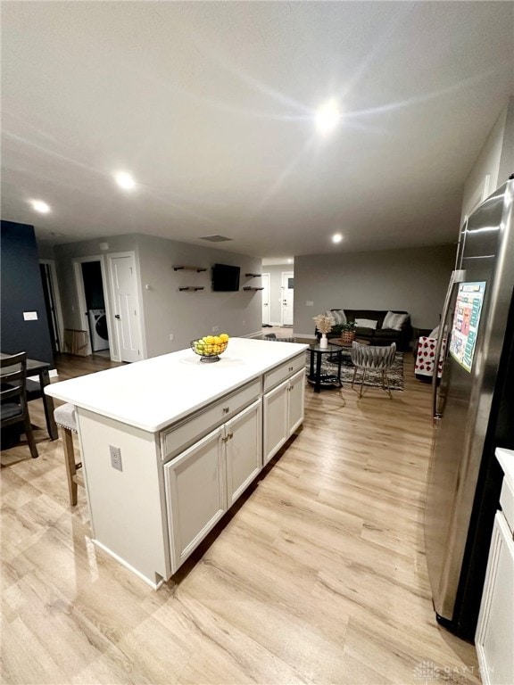 6655 Roycroft Dr, Middletown, OH 45042 - kitchen featuring a kitchen island, washer / clothes dryer, light wood finished floors, recessed lighting, and light countertops