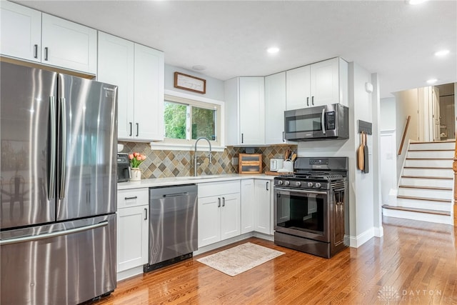 4629 Wicklow Dr, Middletown, OH 45042 - kitchen with stainless steel appliances, light countertops, light wood-type flooring, white cabinetry, and tasteful backsplash
