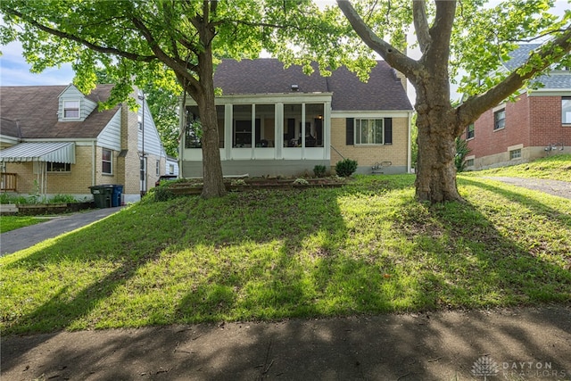 2311 Alpine Way, Dayton, OH 45406 - view of front of home featuring brick siding, a sunroom, a front yard, and a shingled roof