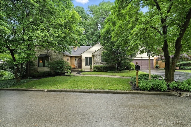 1314 Red Bud Trl, Dayton, OH 45409 - view of property hidden behind natural elements with stone siding, concrete driveway, a front yard, and a garage
