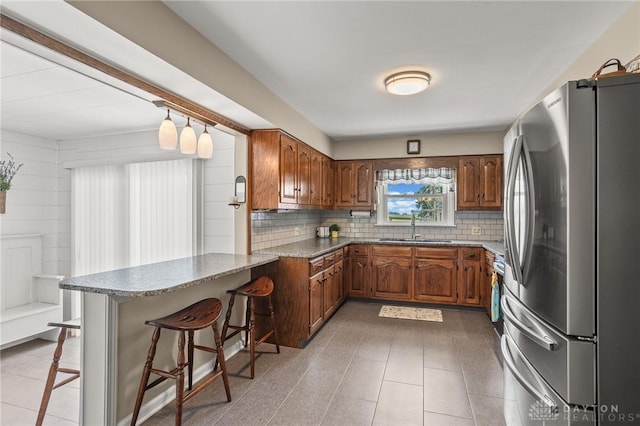 6977 Alternate State Route 49, Arcanum, OH 45304 - kitchen with freestanding refrigerator, a peninsula, brown cabinetry, and a kitchen bar