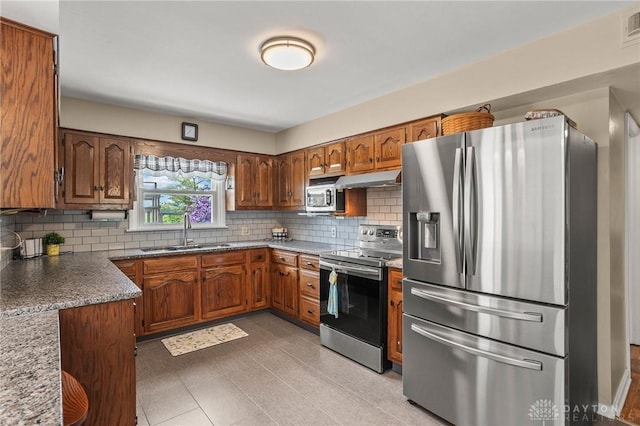 6977 Alternate State Route 49, Arcanum, OH 45304 - kitchen with appliances with stainless steel finishes, under cabinet range hood, brown cabinetry, and backsplash