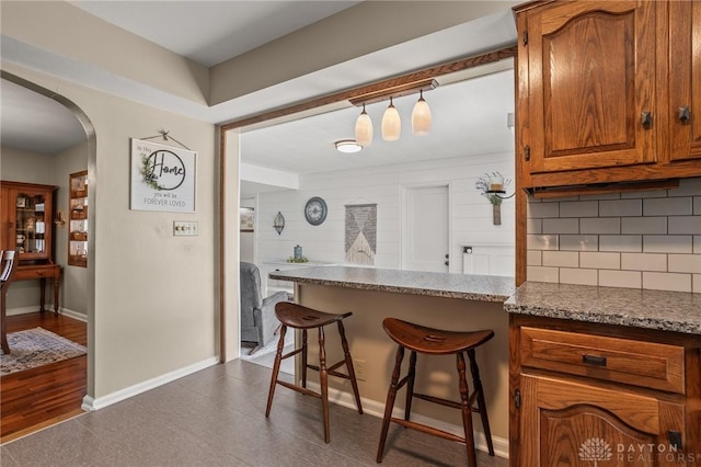 6977 Alternate State Route 49, Arcanum, OH 45304 - kitchen featuring brown cabinets, tasteful backsplash, arched walkways, a breakfast bar area, and a peninsula