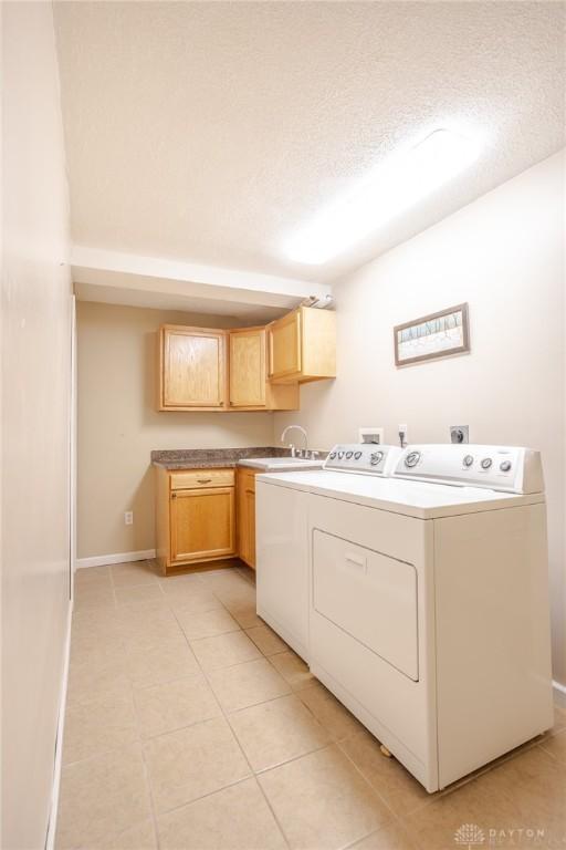 6437 Sun Ridge Dr, Waynesville, OH 45068 - laundry area with washing machine and dryer, light tile patterned floors, cabinet space, and a textured ceiling
