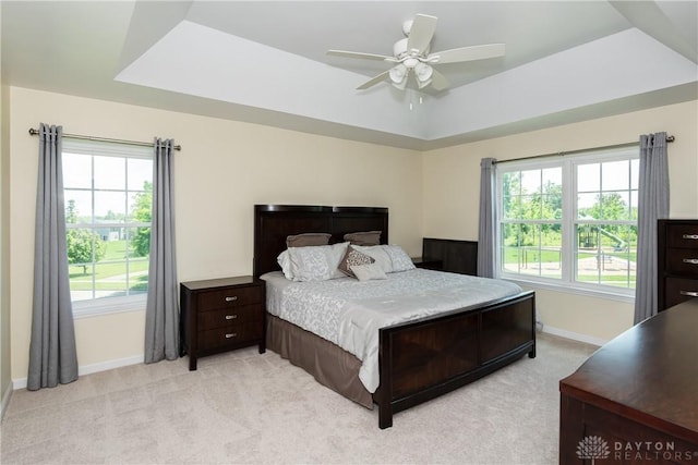 2384 Flyway Ct, Beavercreek, OH 45431 - bedroom with light colored carpet, multiple windows, a tray ceiling, and a ceiling fan