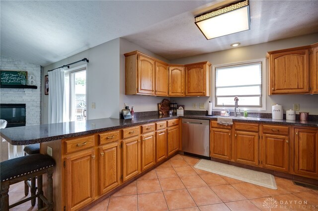 6426 Anvil Dr, Waynesville, OH 45068 - kitchen featuring dishwasher, a peninsula, plenty of natural light, brown cabinetry, and vaulted ceiling