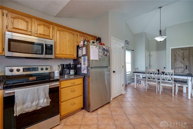 6426 Anvil Dr, Waynesville, OH 45068 - kitchen featuring appliances with stainless steel finishes, lofted ceiling, light tile patterned floors, dark countertops, and decorative light fixtures