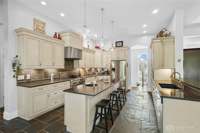 7921 Locust Grove Ct, Springboro, OH 45066 - kitchen featuring cream cabinets, stainless steel appliances, arched walkways, dark stone countertops, and recessed lighting