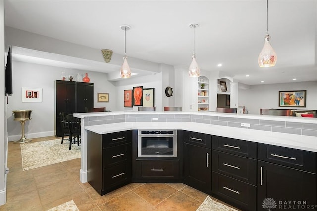 7921 Locust Grove Ct, Springboro, OH 45066 - kitchen with stainless steel oven, dark cabinets, light countertops, recessed lighting, and decorative light fixtures