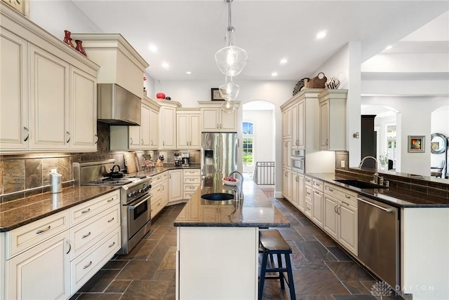 7921 Locust Grove Ct, Springboro, OH 45066 - kitchen with stainless steel appliances, cream cabinetry, arched walkways, stone tile floors, and recessed lighting