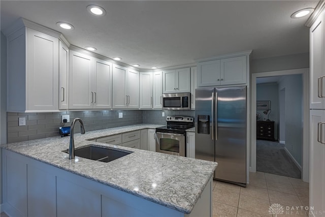 5010 Rhine Way, Centerville, OH 45458 - kitchen featuring appliances with stainless steel finishes, a peninsula, light tile patterned floors, light stone countertops, and decorative backsplash