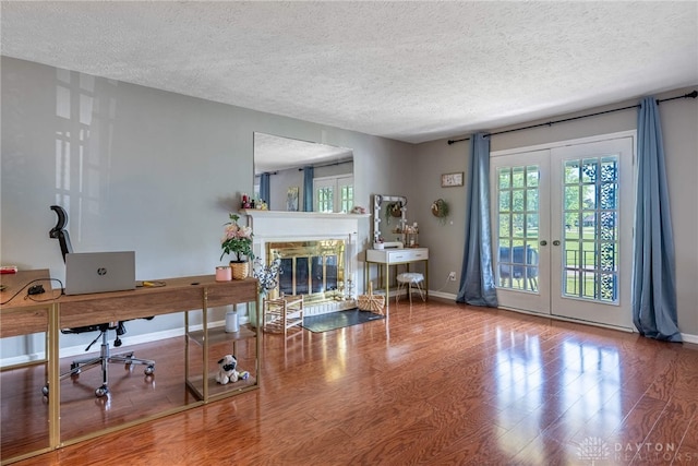 9031 S Normandy Ln, Washington Twp, OH 45458 - living room with french doors, a textured ceiling, a glass covered fireplace, wood finished floors, and a desk