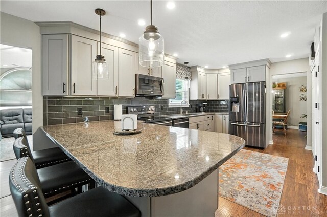 3166 Green Turtle Dr, Butler Twp, OH 45414 - kitchen featuring appliances with stainless steel finishes, a peninsula, wood finished floors, stone countertops, and recessed lighting
