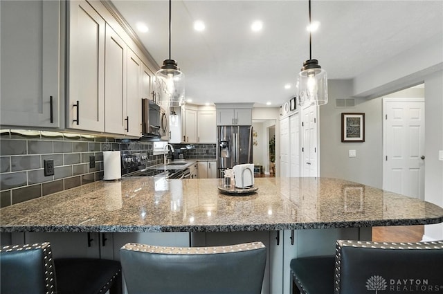 3166 Green Turtle Dr, Butler Twp, OH 45414 - kitchen featuring stainless steel appliances, a peninsula, tasteful backsplash, dark stone countertops, and pendant lighting