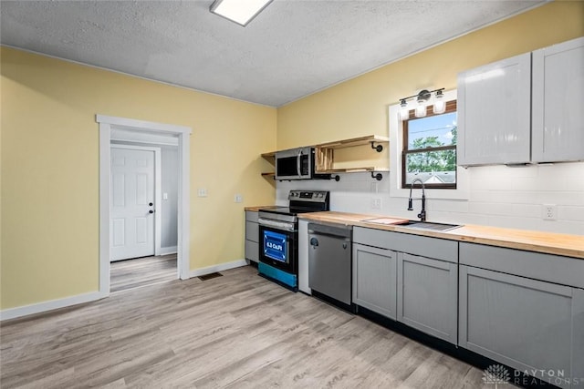 506 Virginia Ave, Troy, OH 45373 - kitchen featuring stainless steel appliances, wood counters, gray cabinetry, open shelves, and a textured ceiling