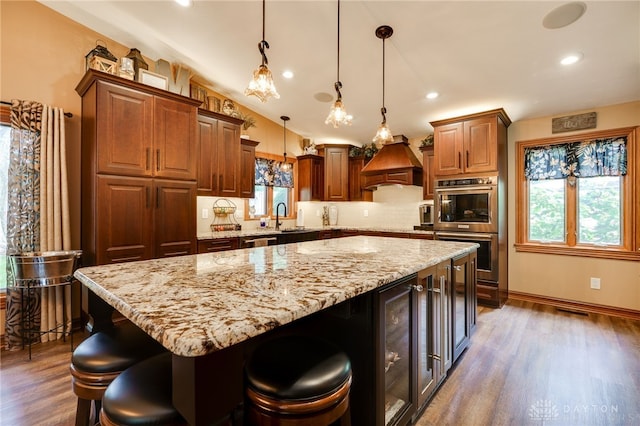 5516 Anne Ln, Washington Twp, OH 45459 - kitchen with stainless steel double oven, custom range hood, wood finished floors, light stone countertops, and recessed lighting