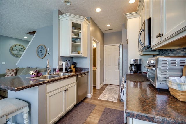9270 Great Lakes Cir Unit 9270, Washington Twp, OH 45458 - kitchen featuring stainless steel appliances, a peninsula, dark countertops, glass insert cabinets, and light wood finished floors