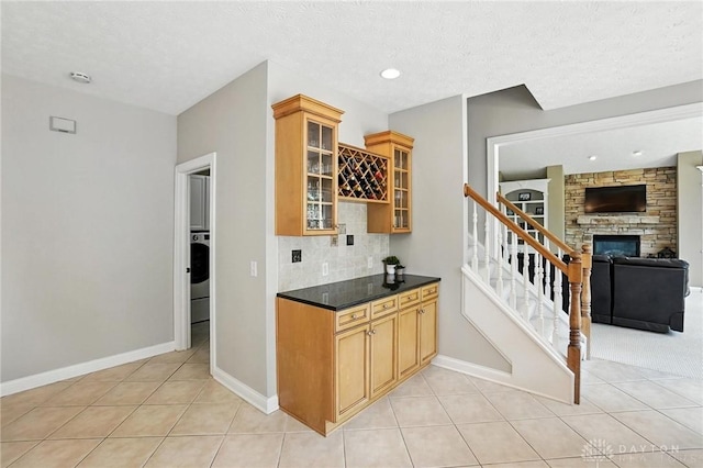 10598 Falls Creek Ln, Washington Twp, OH 45458 - bar with stairway, light tile patterned floors, tasteful backsplash, recessed lighting, and a fireplace