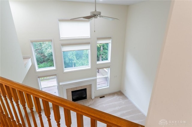 2540 Early Spring Ct, Dayton, OH 45459 - unfurnished living room featuring a tile fireplace, light colored carpet, a high ceiling, ceiling fan, and stairway