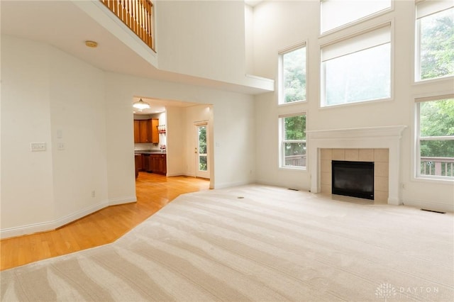 2540 Early Spring Ct, Dayton, OH 45459 - unfurnished living room with a high ceiling, light wood-style flooring, and a tiled fireplace