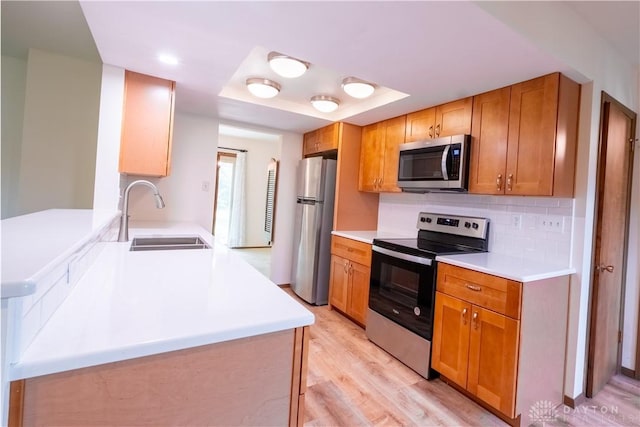 4425 E Entrada Dr, Beavercreek, OH 45431 - kitchen featuring appliances with stainless steel finishes, light wood-style floors, decorative backsplash, light countertops, and a peninsula