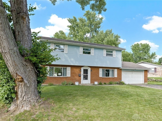 6118 Carnation Rd, Dayton, OH 45449 - colonial house featuring a garage, asphalt driveway, a front yard, and brick siding