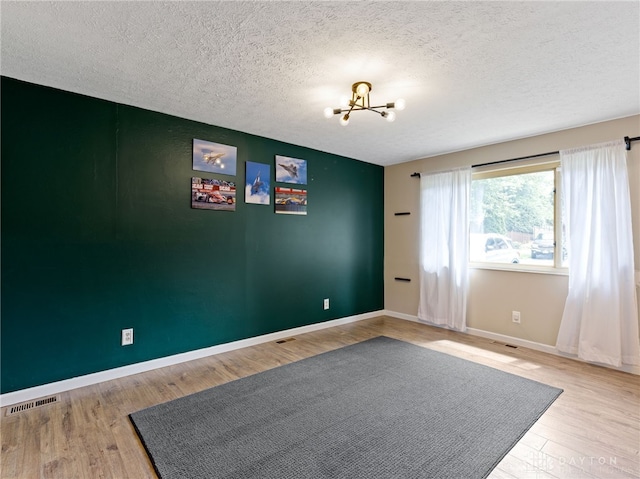 6118 Carnation Rd, Dayton, OH 45449 - unfurnished room featuring a chandelier, wood finished floors, and a textured ceiling