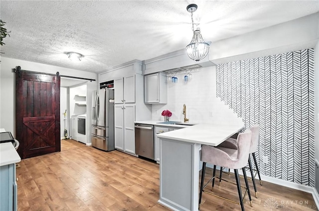 8052 Timberlodge Trl, Washington Twp, OH 45458 - kitchen with stainless steel appliances, a barn door, light countertops, a peninsula, and a breakfast bar