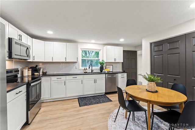 1209 Maple St, Troy, OH 45373 - kitchen with stainless steel appliances, light wood finished floors, dark countertops, tasteful backsplash, and recessed lighting