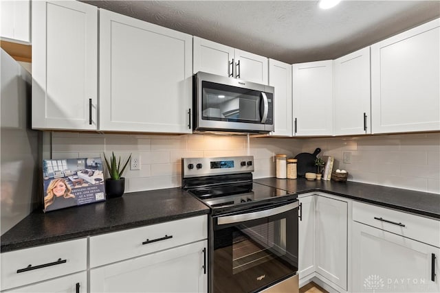 1209 Maple St, Troy, OH 45373 - kitchen with appliances with stainless steel finishes, white cabinets, tasteful backsplash, and dark countertops