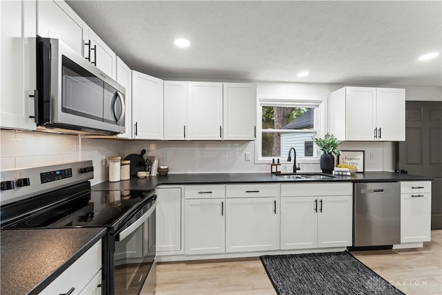1209 Maple St, Troy, OH 45373 - kitchen featuring appliances with stainless steel finishes, light wood finished floors, decorative backsplash, recessed lighting, and white cabinets