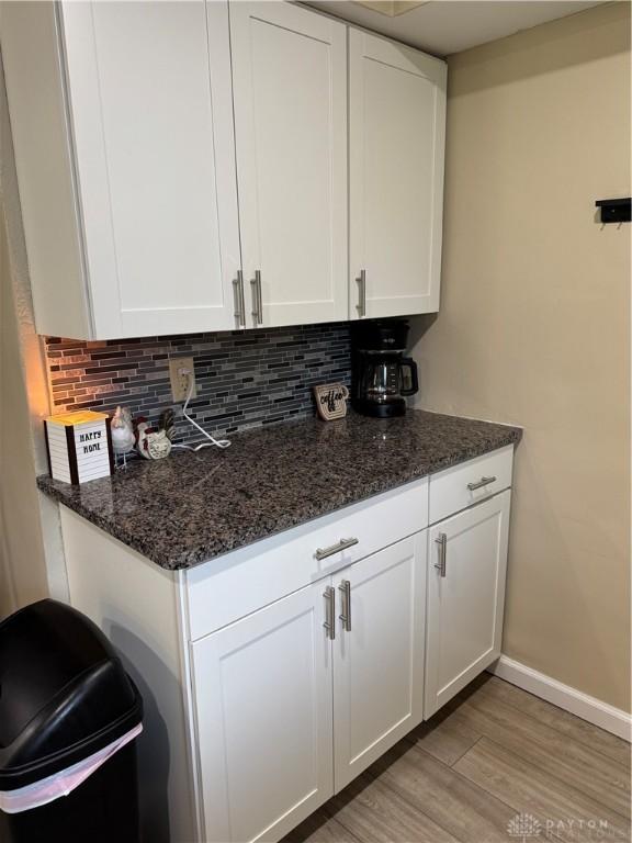 6346 Apache St, Dayton, OH 45424 - kitchen featuring white cabinets, tasteful backsplash, light wood-type flooring, and dark stone countertops