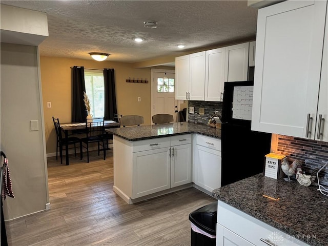 6346 Apache St, Dayton, OH 45424 - kitchen with a peninsula, freestanding refrigerator, white cabinets, tasteful backsplash, and a textured ceiling