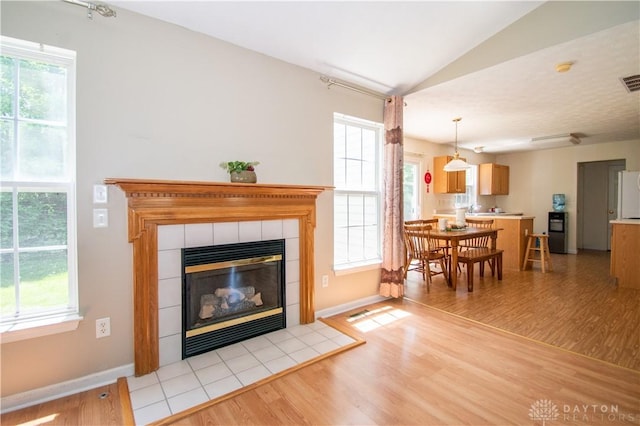3583 King Edward Way, Beavercreek, OH 45431 - living room with light wood-type flooring, vaulted ceiling, a tiled fireplace, and plenty of natural light