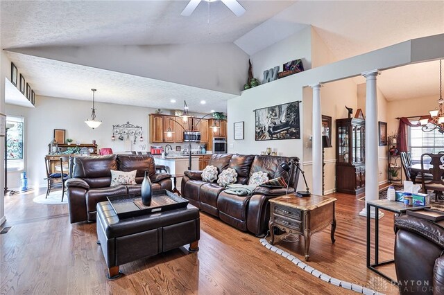 595 Heatherwoode Cir, Springboro, OH 45066 - living room featuring ornate columns, ceiling fan, a chandelier, wood finished floors, and high vaulted ceiling