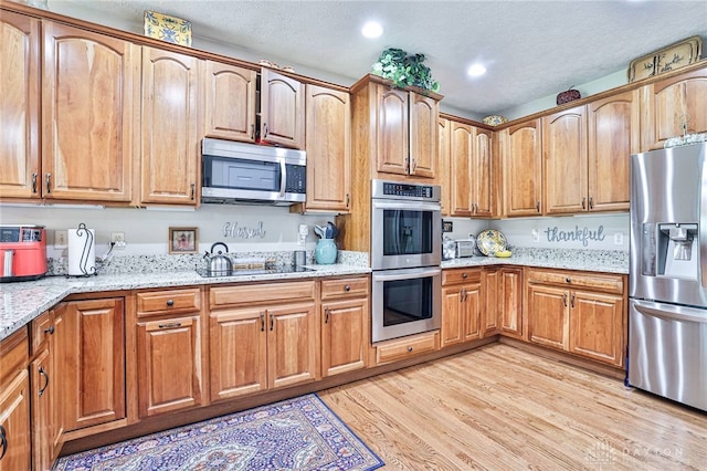 595 Heatherwoode Cir, Springboro, OH 45066 - kitchen featuring appliances with stainless steel finishes, light stone counters, light wood finished floors, a textured ceiling, and recessed lighting