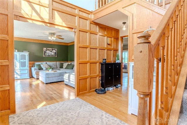 1061 Mcpherson Rd, Xenia, OH 45385 - living area with light wood-style floors, ceiling fan, crown molding, a wainscoted wall, and stairs