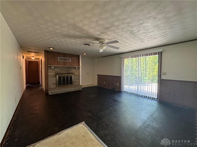 2886 Kemp Rd, Beavercreek, OH 45431 - unfurnished living room featuring a wainscoted wall, a ceiling fan, a fireplace, wooden walls, and tile patterned floors