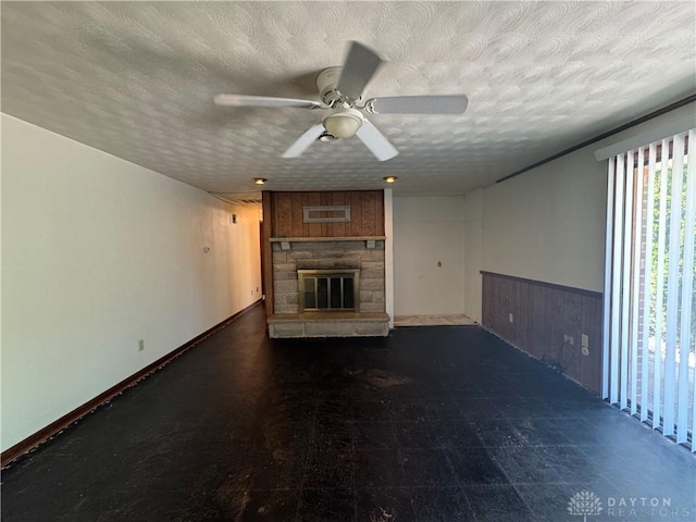 2886 Kemp Rd, Beavercreek, OH 45431 - unfurnished living room featuring ceiling fan, a stone fireplace, a textured ceiling, and a wainscoted wall