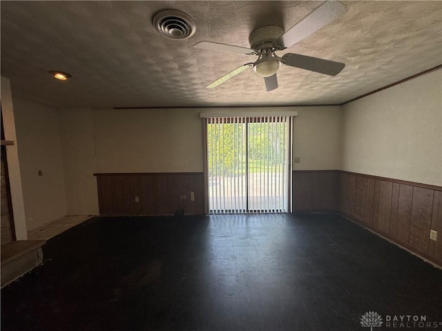 2886 Kemp Rd, Beavercreek, OH 45431 - empty room with wainscoting, a ceiling fan, a textured ceiling, and wooden walls