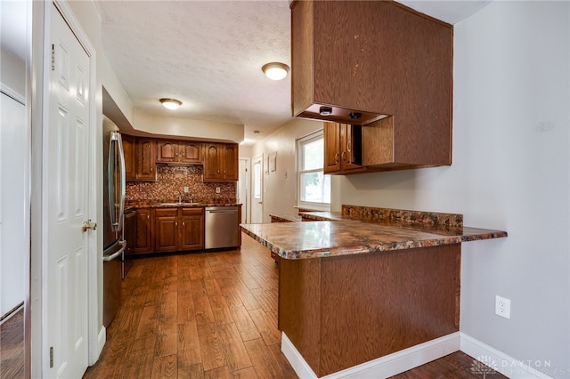 222 Kenderton Trl, Beavercreek, OH 45430 - kitchen featuring stainless steel appliances, a peninsula, dark wood finished floors, brown cabinets, and dark countertops