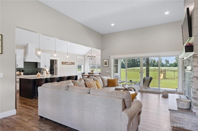 9782 E US Highway 22 And 3, Clarksville, OH 45113 - living room with a chandelier, dark wood-type flooring, high vaulted ceiling, a stone fireplace, and recessed lighting